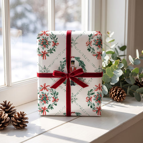 Gift wrapped in Nutcracker Wreaths paper with a burgundy velvet ribbon, on a snowy windowsill